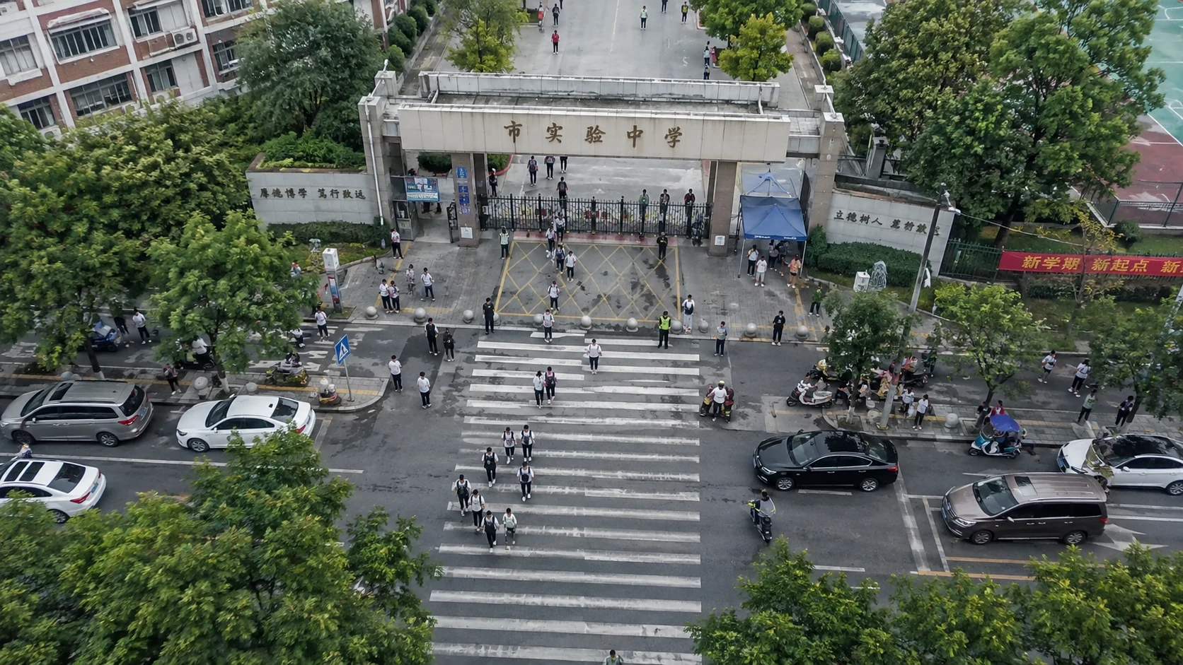 校门人车交汇风险巡查：独立无人机航拍场景与红色目标标注示意